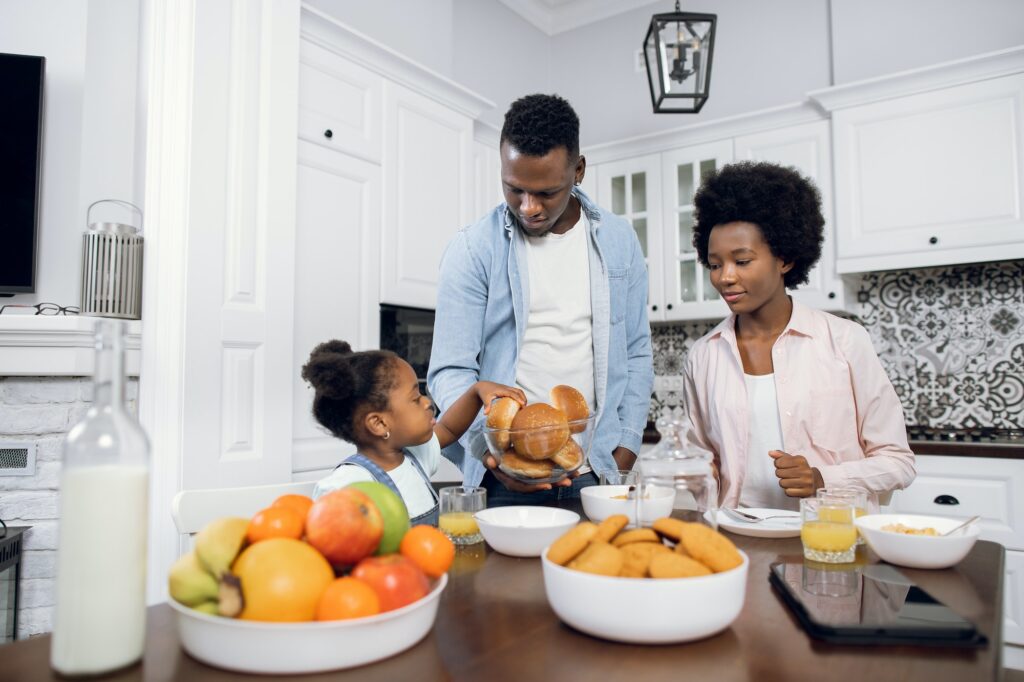 African parents with daughter enjoying breakfast at home